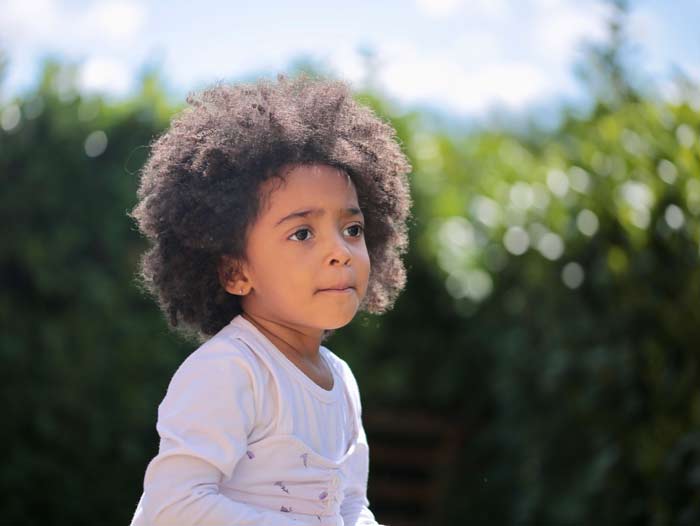 A young child with a big afro looking at the camera.