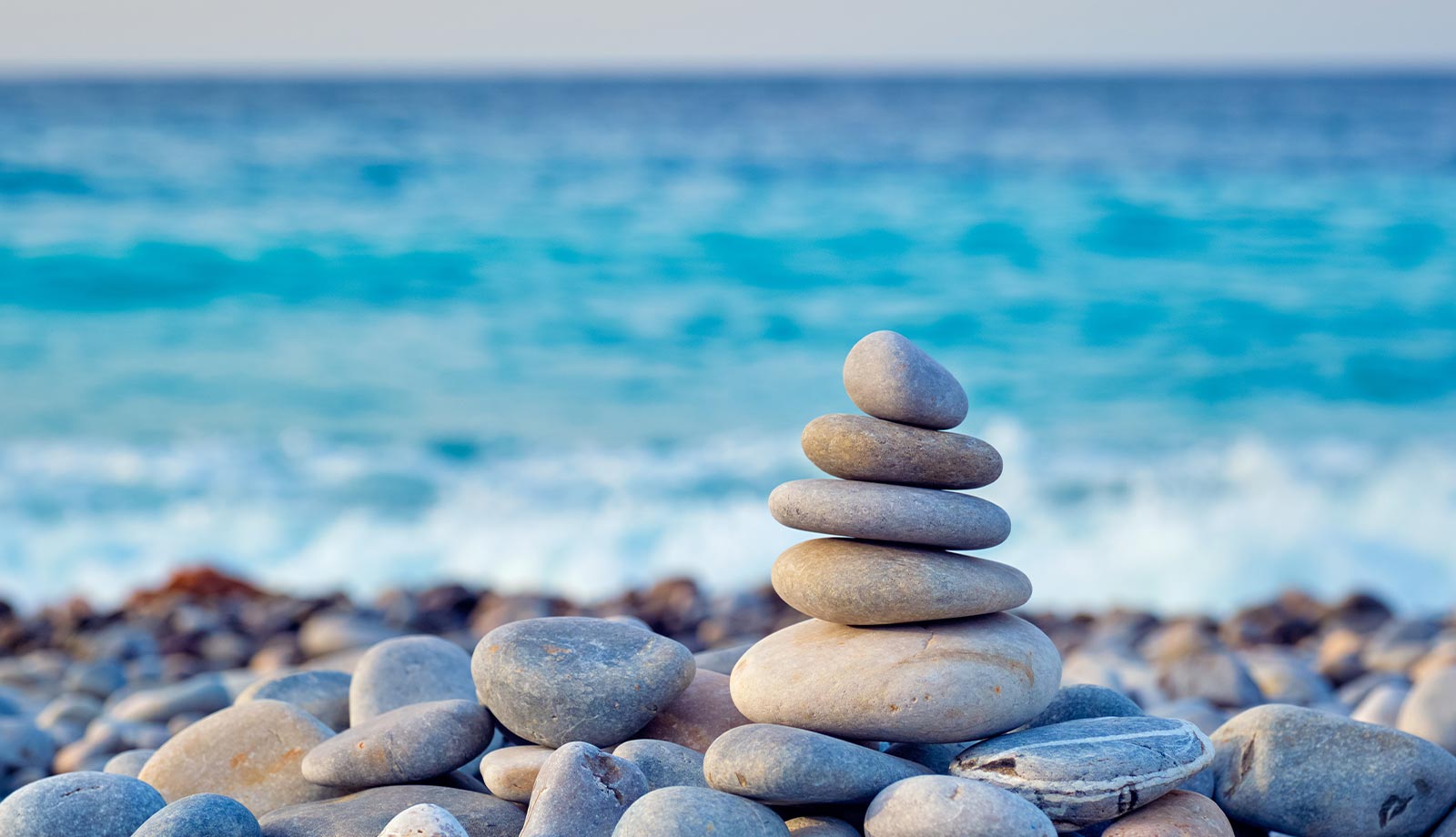 A stack of rocks on the beach near water