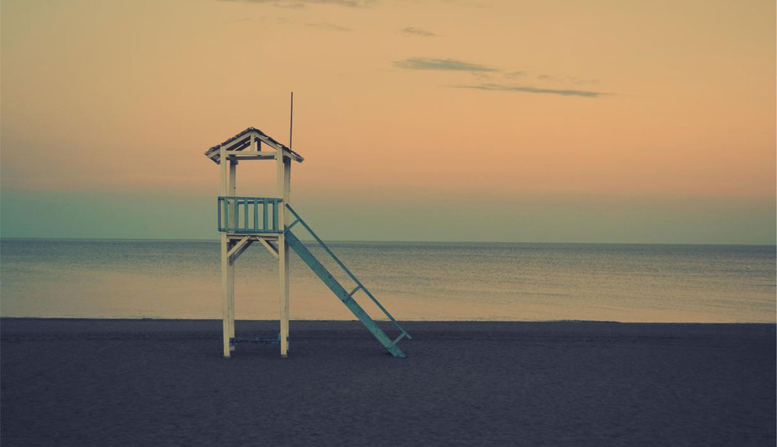 A lifeguard tower on the beach at sunset.