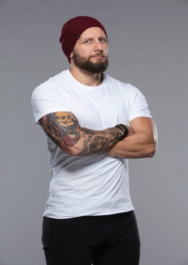 A man with tattoos and a beard wearing a white shirt